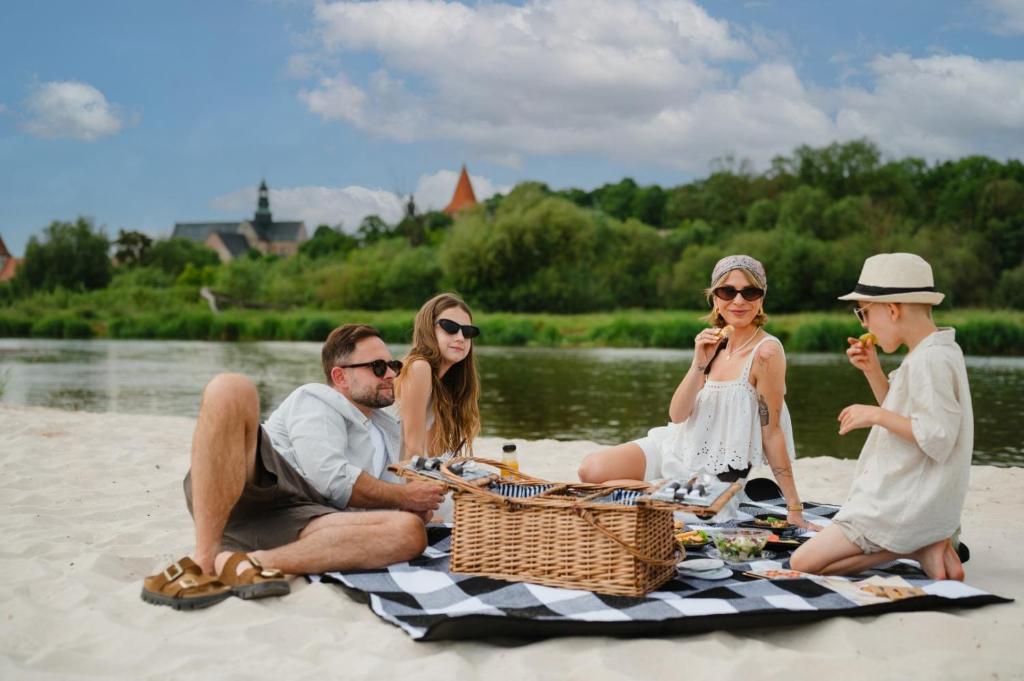 a group of people sitting on a picnic blanket on the beach at Hotel Podklasztorze in Sulejów