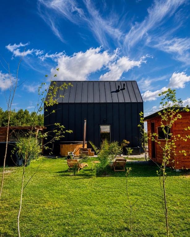 a black house on a green yard with a building at Domki Grabina in Grabina