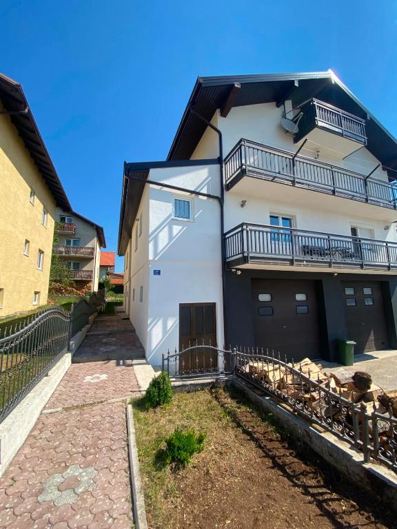 a white building with a balcony and some sheep at Kuća Latice in Tomislavgrad