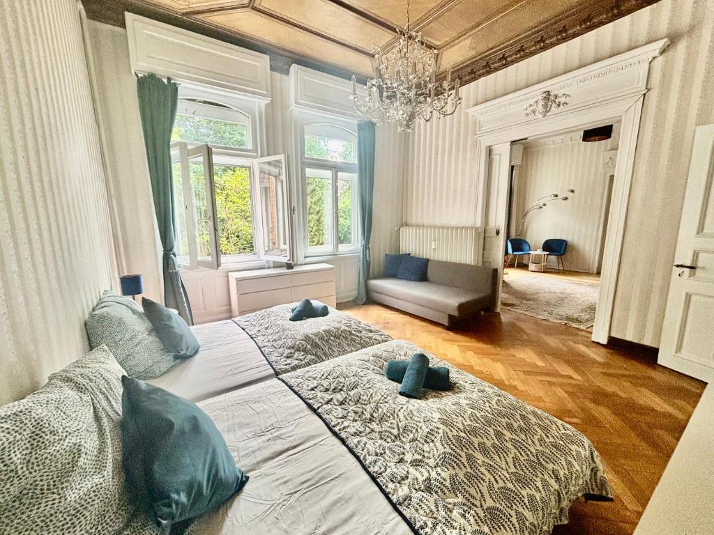 a bedroom with two beds and a chandelier at Villa Sartorius - charmant und denkmalgeschützt wohnen nahe Göttingen in Bovenden