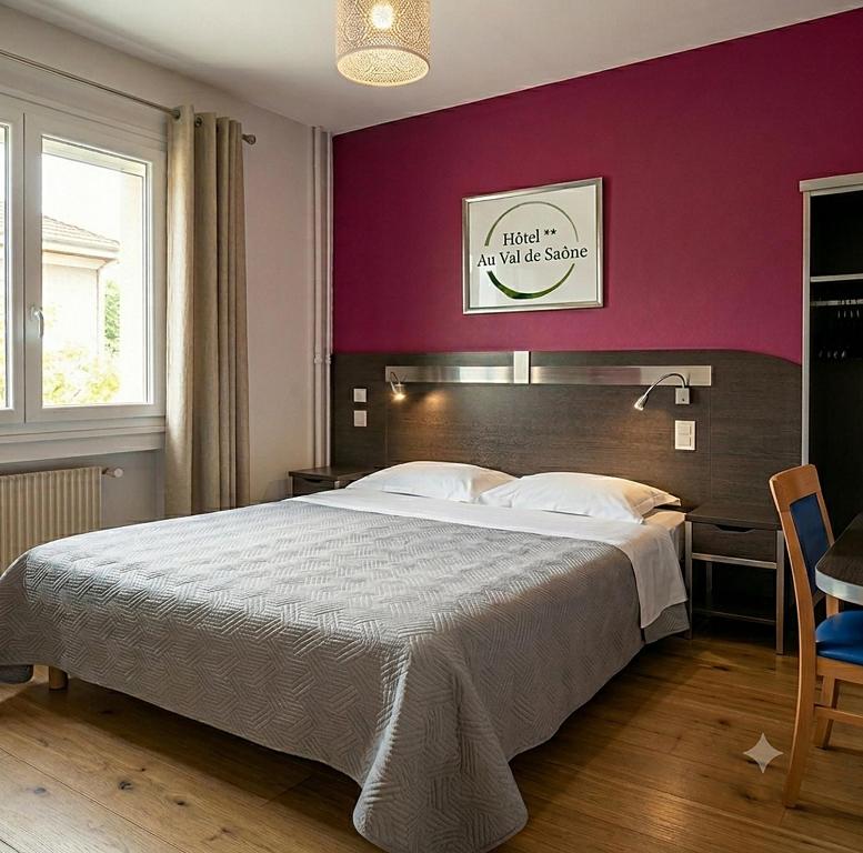 a bedroom with a large bed with a purple wall at Hôtel Au Val De Saône PARKING GRATUIT in Sathonay-Camp