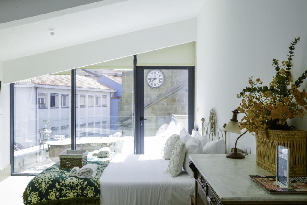 a bedroom with a bed and a window with a clock at Casa Matriz Séc. XVI | Double or Twin w/ balcony in Penafiel