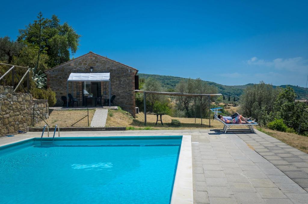a swimming pool in front of a stone house at PoloTuristicoUmbria Rustico con Piscina Vista Lago in Passignano sul Trasimeno