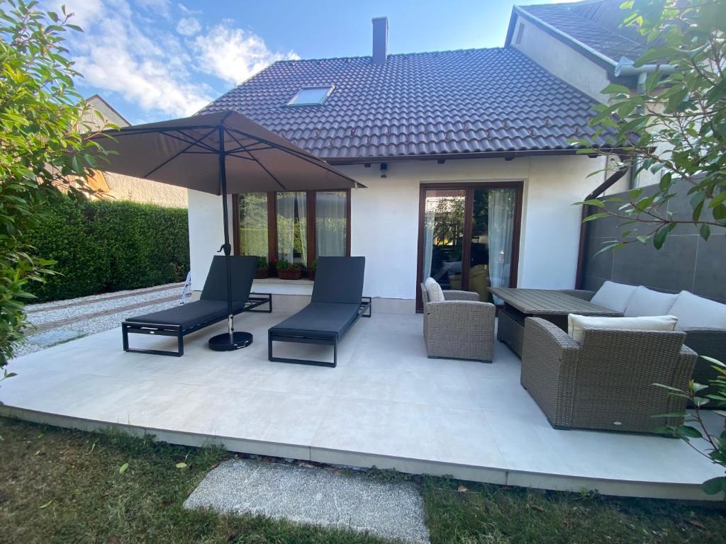 a patio with chairs and an umbrella at Erelia Cottage in Bük