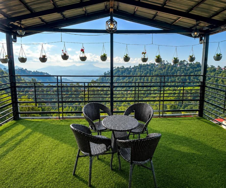 a table and chairs on a balcony with a view at Dharvi Kasauli Heavens in Kasauli