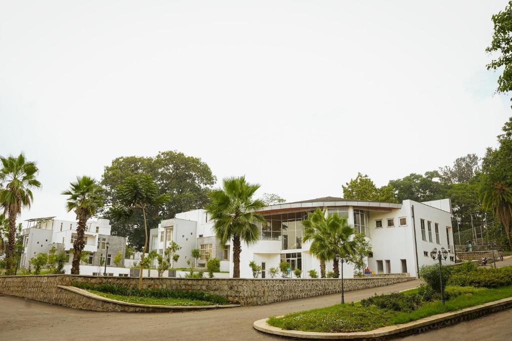 a white building with palm trees in front of it at Jimma Palace Hotel in Jīma
