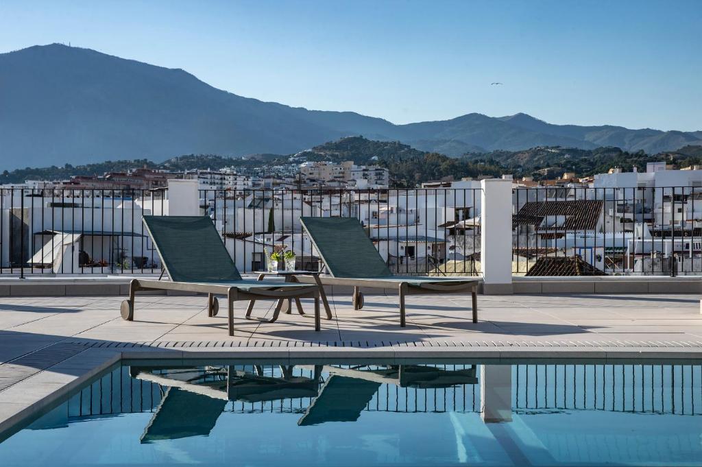 two chairs and a table next to a swimming pool at Hotel Estepona Patio in Estepona