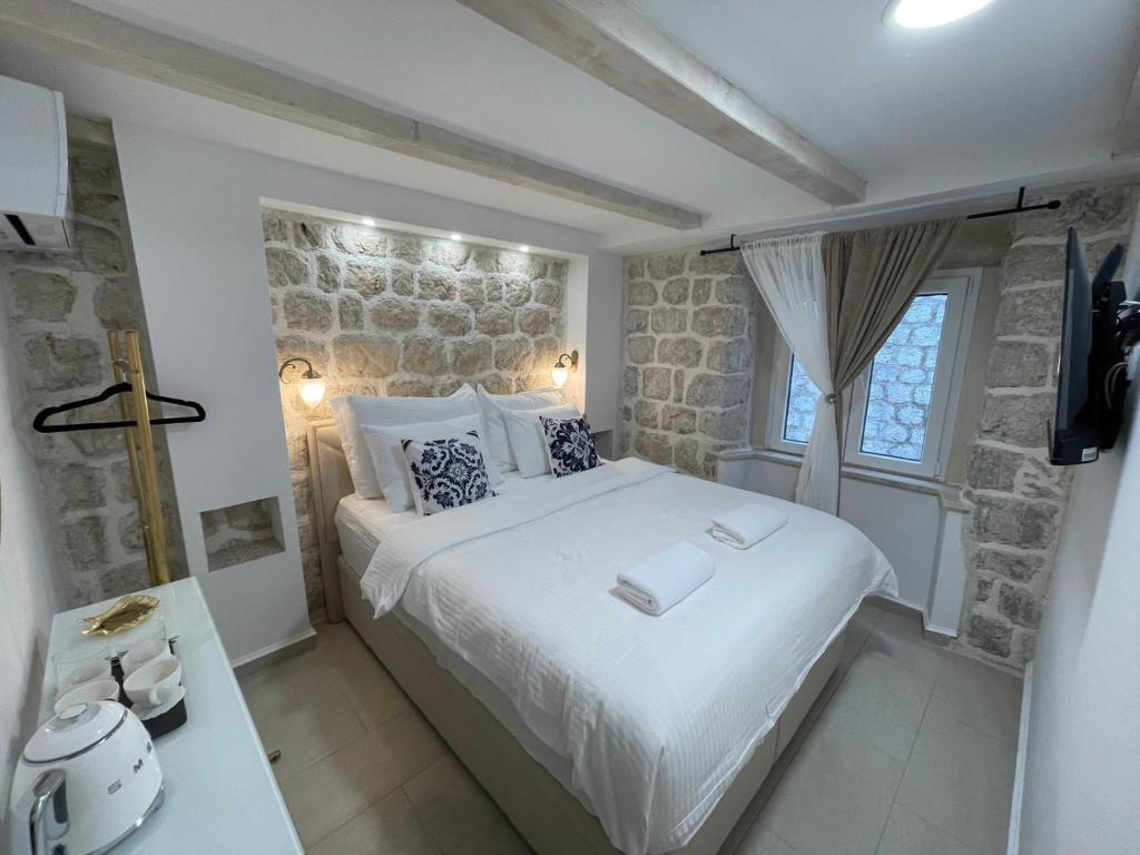 a bedroom with a large bed and a stone wall at StonSoldo Rooms in Ston