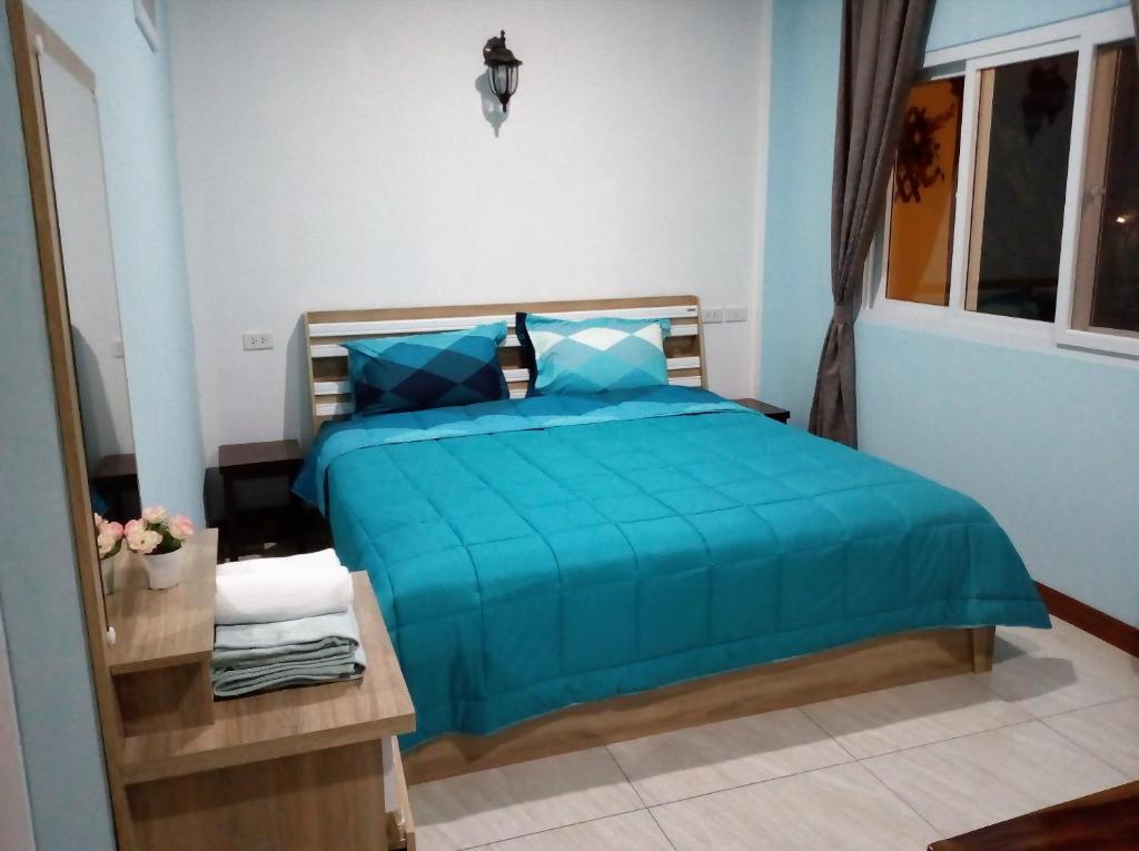 a bedroom with a bed with a blue comforter at Baan Penny in Phra Nakhon Si Ayutthaya