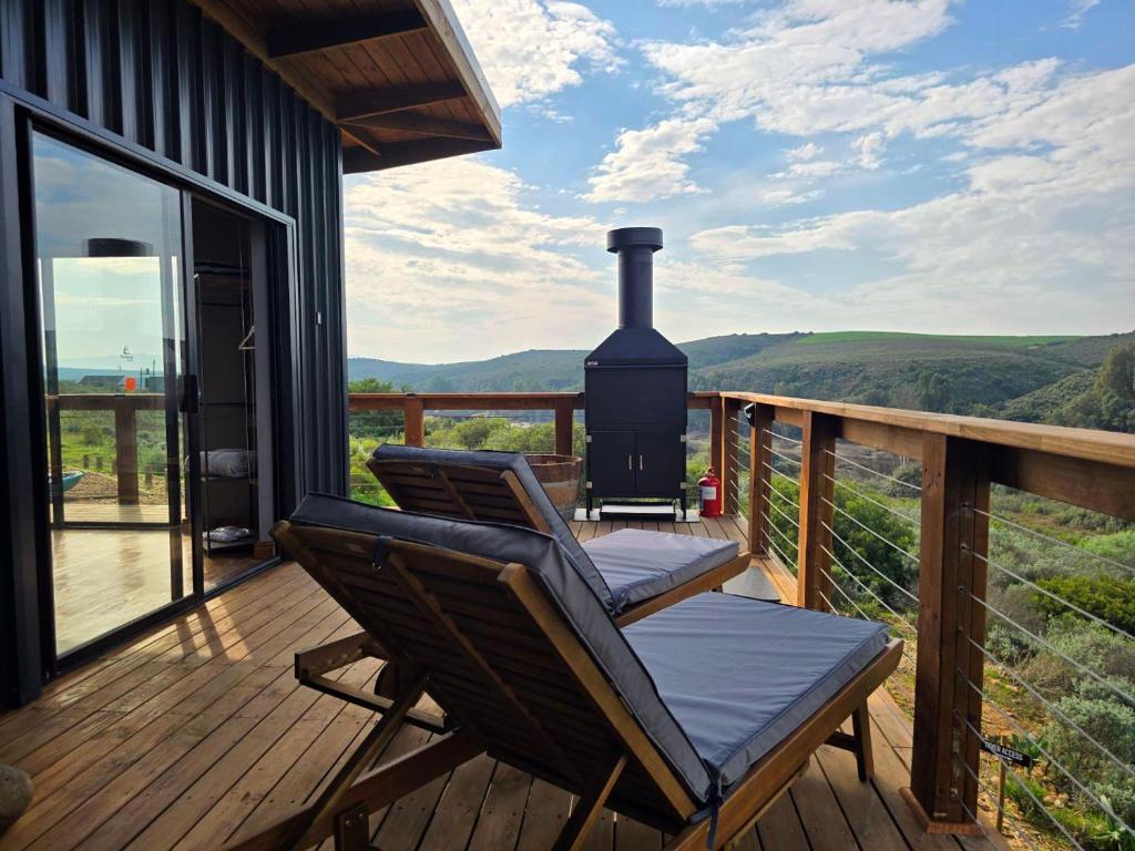 a deck with a lounge chair and a fireplace at Renosterveld Eco Pods in Swellendam