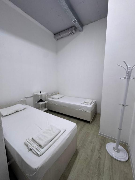 a white room with two beds and a lamp at Хостел in Astana