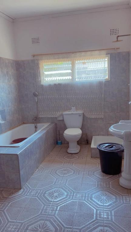 a bathroom with a tub and a toilet and a sink at Quantico Guest house villa in Ndola