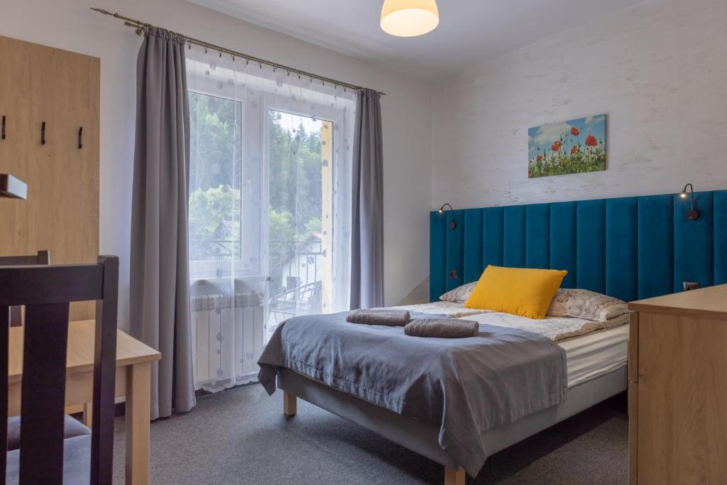 a bedroom with a bed with a blue headboard and a window at Willa Mak in Krynica Zdrój