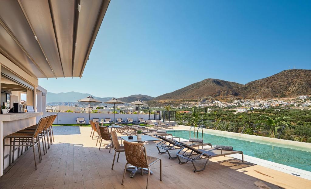 a patio with tables and chairs and a pool at Enorme Epavli Urban Living in Hersonissos