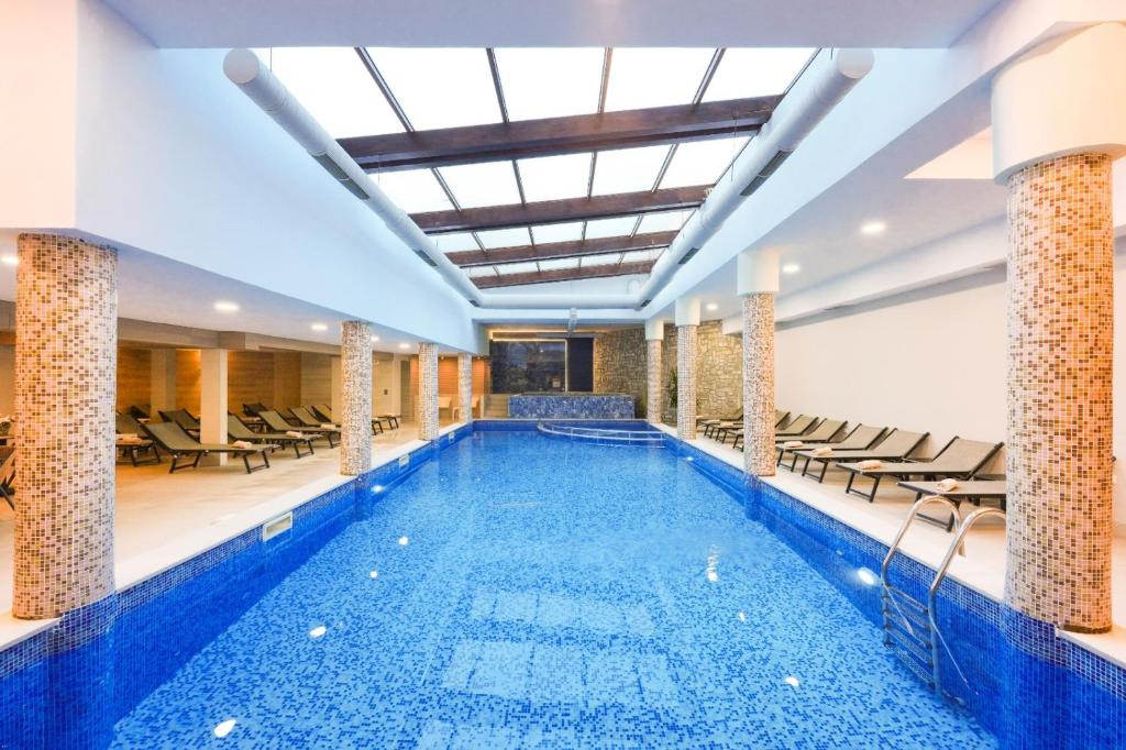 a large swimming pool with chairs in a building at Predela LUX Aparthotel in Bansko