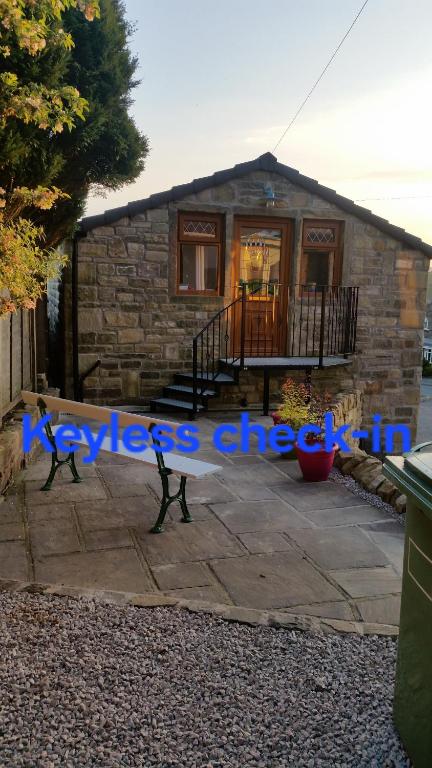 a small stone house with a sign in front of it at Stone Eater in Marsden