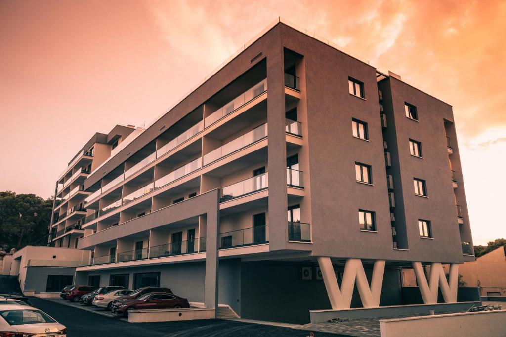 a large building with cars parked in a parking lot at Amfora-modern apartments with pool in Makarska