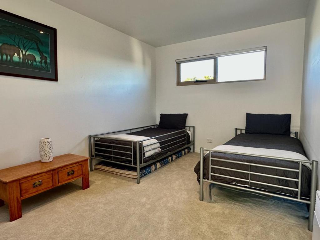 a room with two beds and a table and a window at Waterfront Primrose Retreat in Primrose Sands