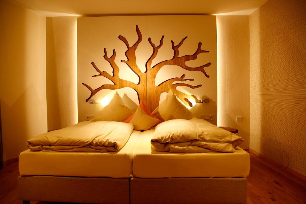 Flair Hotel Nieder في بيستفيغ: غرفة نوم مع سرير مع شجرة على الحائط