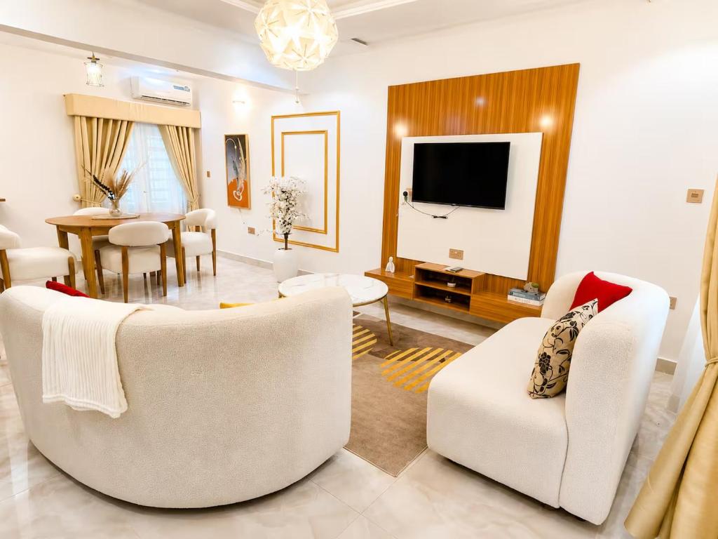 a living room with white furniture and a dining room at Little Afrika in Port Harcourt