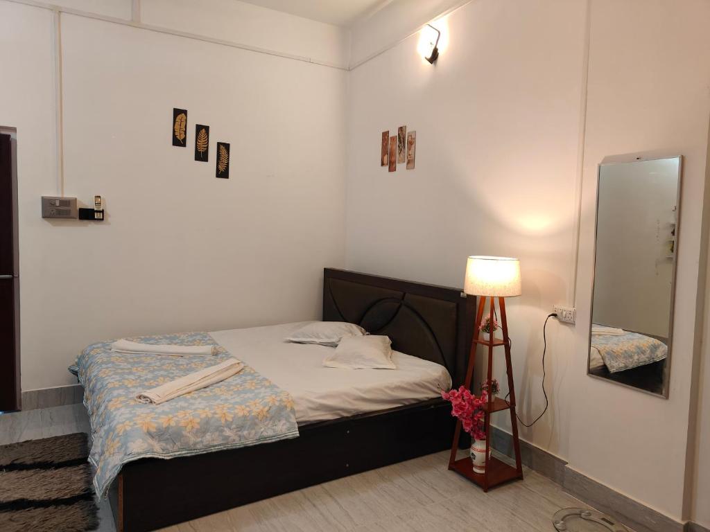 a small bedroom with a bed and a lamp at PINES and PETALS in Jorhat
