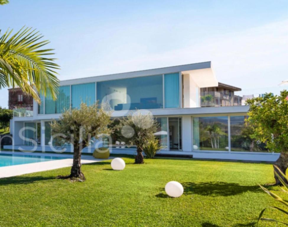 a villa with a swimming pool and a yard at Villa White Glass in Fiumefreddo di Sicilia