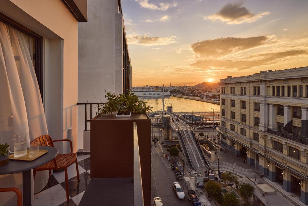 ein Balkon mit Blick auf die Stadt bei Sonnenuntergang in der Unterkunft Mural Piraeus Hotel in Piräus