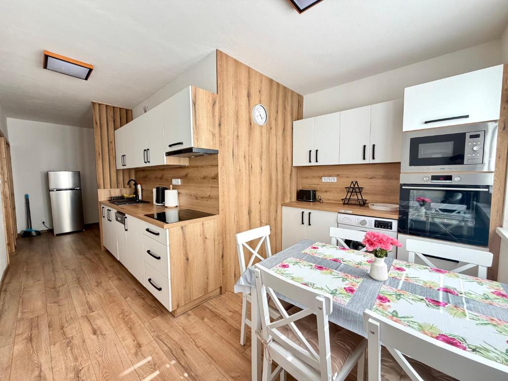 a kitchen with white cabinets and a table with chairs at Apartmánový byt Flower in Kadaň