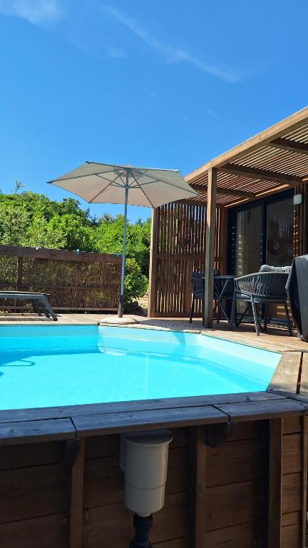 a large blue pool with an umbrella on a deck at TINY HOUSE avec piscine "La Bernadette" villa Sisyphe in Le Thoronet