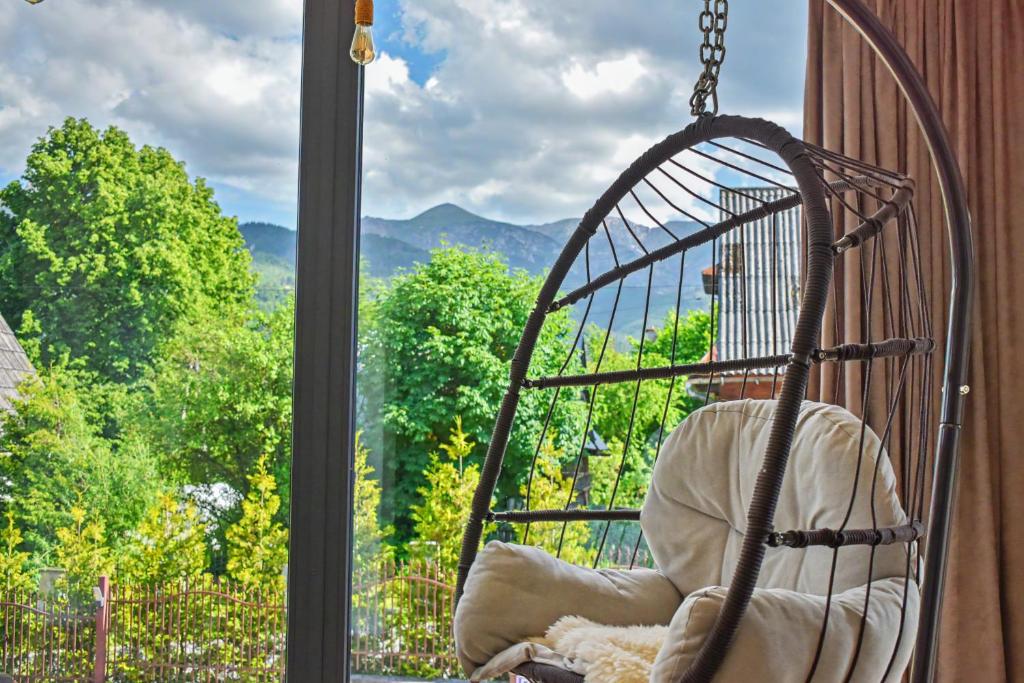a swinging chair in a window with a view at Apartamenty Widokowe Pod Lasem in Kościelisko