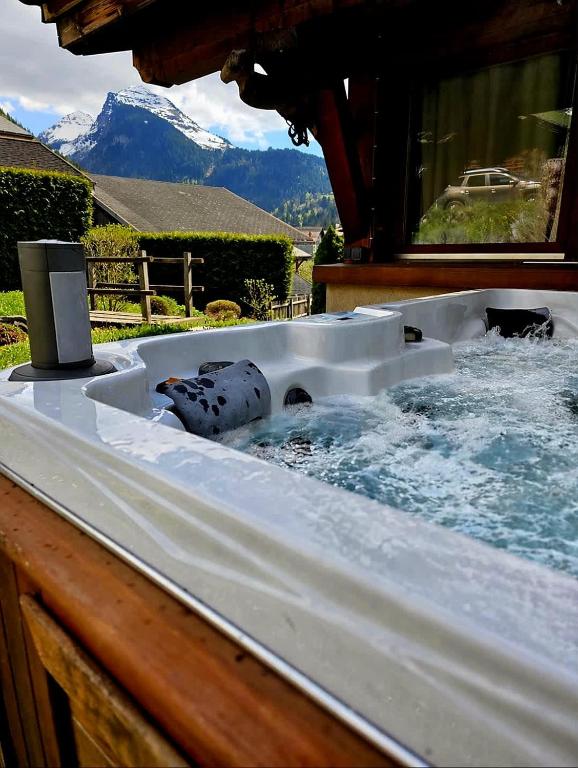 a hot tub in a backyard with mountains in the background at Large Superior Style Chalet - Central Location in Morzine