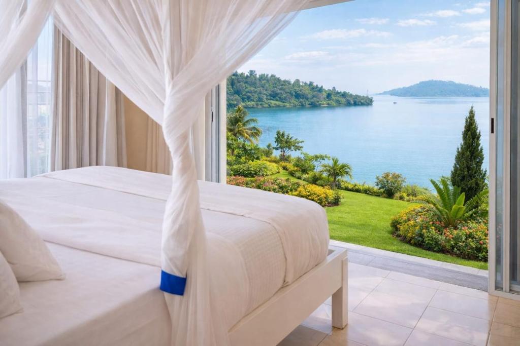 a bedroom with a bed and a view of the water at Mariebu Beach Resort in Buhongo