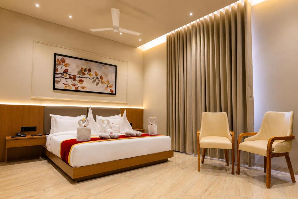 a hotel room with a bed and two chairs at LUXURIA INN By CHANDAN in Junagadh