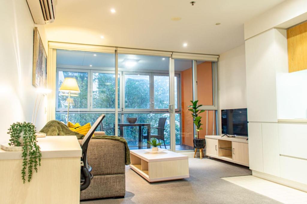 a living room with a couch and a large window at Koala Nest Central Adelaide 1BR Apartment with Pool & Sauna - Koala Stay in Adelaide