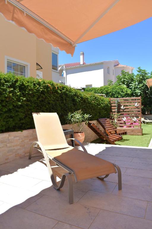 a white chair sitting under an umbrella on a patio at Apartmani Benedetti in Povljana