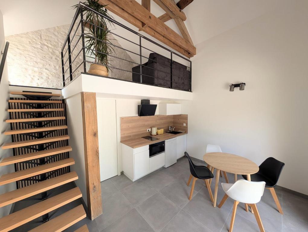 a room with a staircase and a table and chairs at L'étable du Moulin in Mer