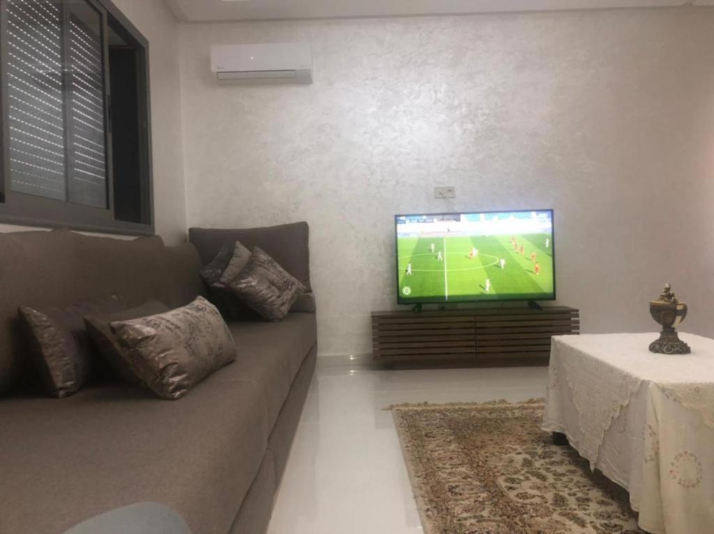 a living room with a couch and a flat screen tv at Appartement mansoria in Mansouria