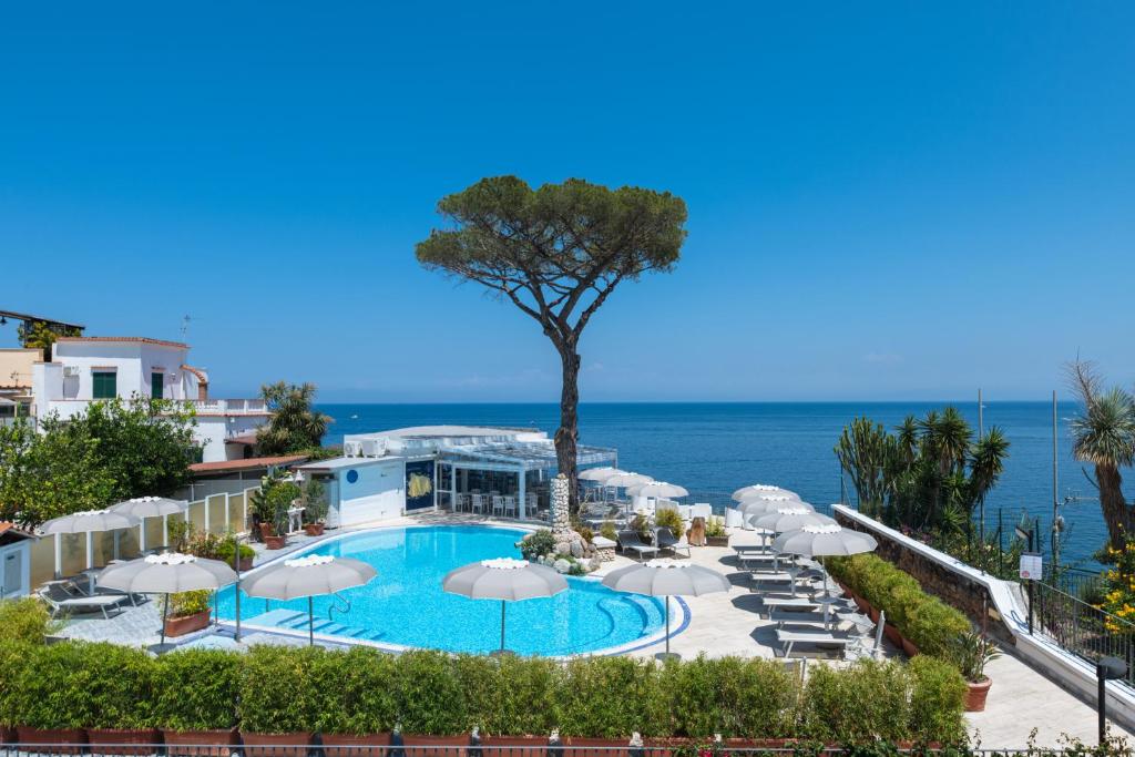 a view of a pool with umbrellas and the ocean at Hotel L'Approdo in Casamicciola Terme