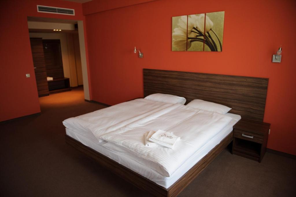 a bedroom with a large white bed with an orange wall at Taurus Ładna in Ładna