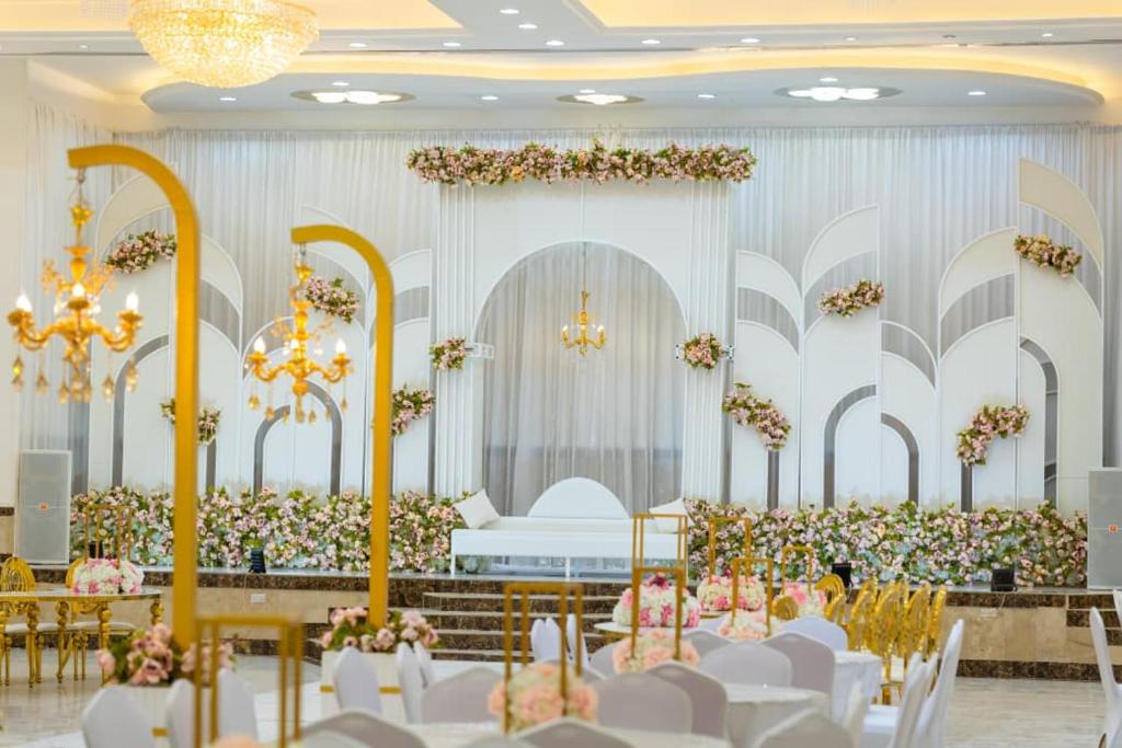 a banquet hall with white chairs and flowers at القاعة الملكية للافراح والموتمرات in Baţḩāʼ