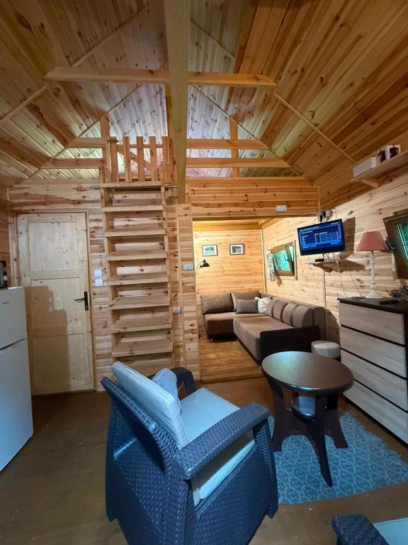 a log cabin living room with a couch and a table at Cottage with access to the lake in Tarnów Jezierny