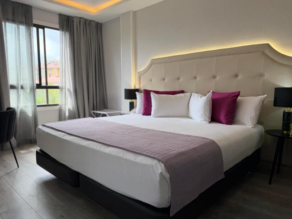 a bedroom with a large bed with purple and white pillows at Hotel Faranda Los Tilos, Ascend Hotel Collection in Santiago de Compostela