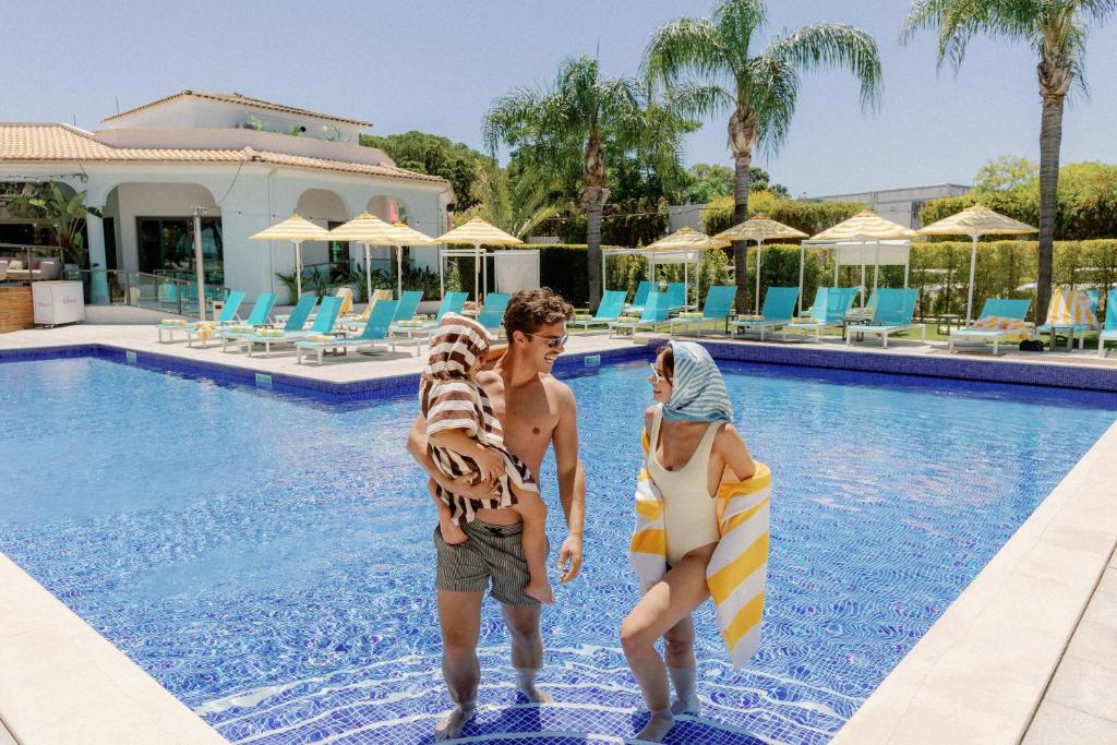 a group of people walking into a swimming pool at The Magnolia Hotel in Quinta do Lago