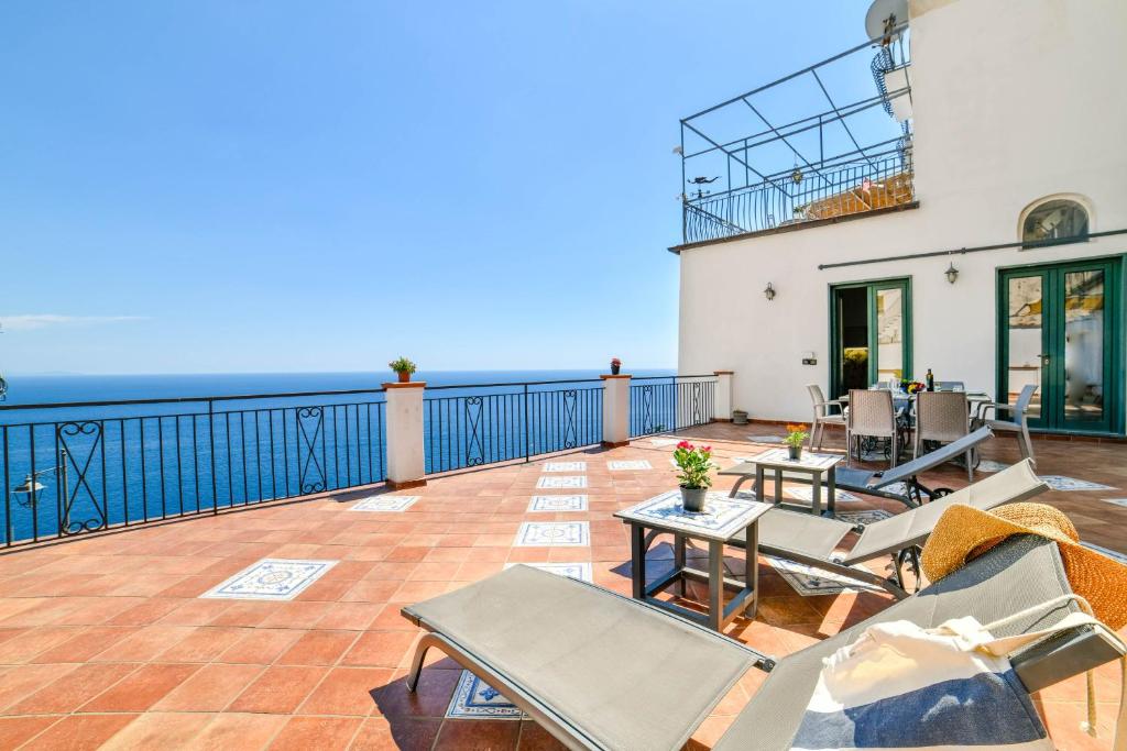 a patio with chairs and tables on a balcony at Terrazza di Rosa - sea view in Praiano