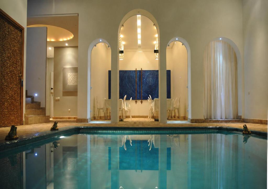 a swimming pool with a table and chairs in a building at Riad Zyo in Rabat