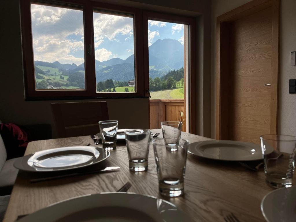 a table with plates and glasses and a view of mountains at Haus Casimir in Reith im Alpbachtal