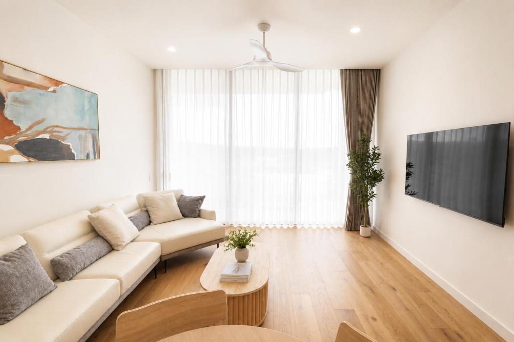 a living room with a couch and a tv at Lumi Residence Robina in Gold Coast