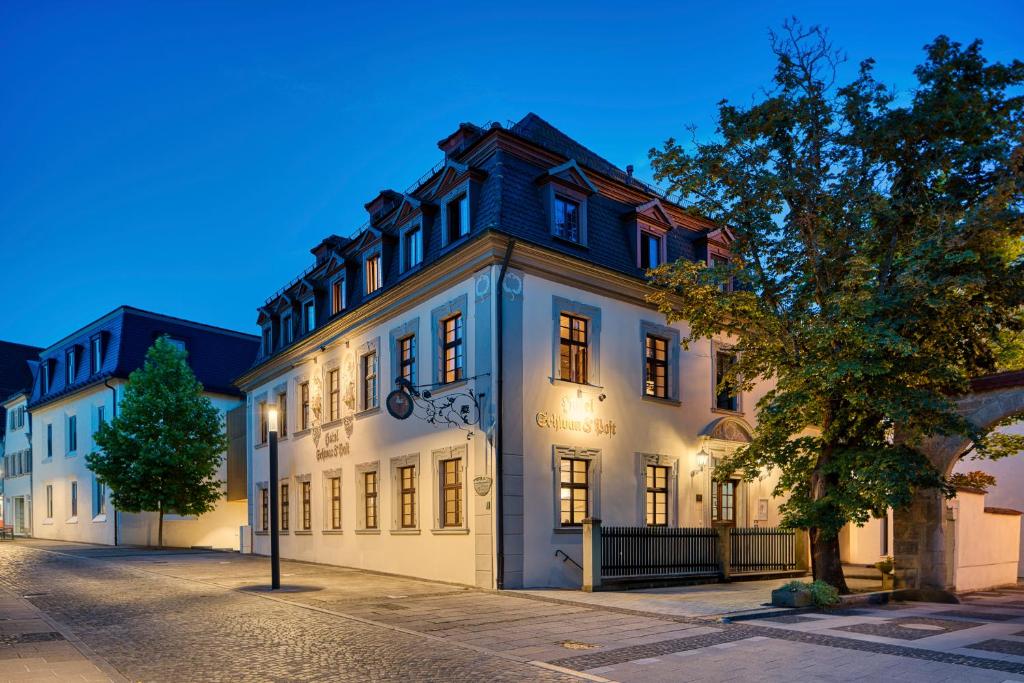 a large white building on a street at night at Hotel Schwan & Post in Bad Neustadt an der Saale