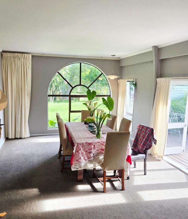 a dining room with a table and chairs and a window at Amore Manor Auckland in Auckland