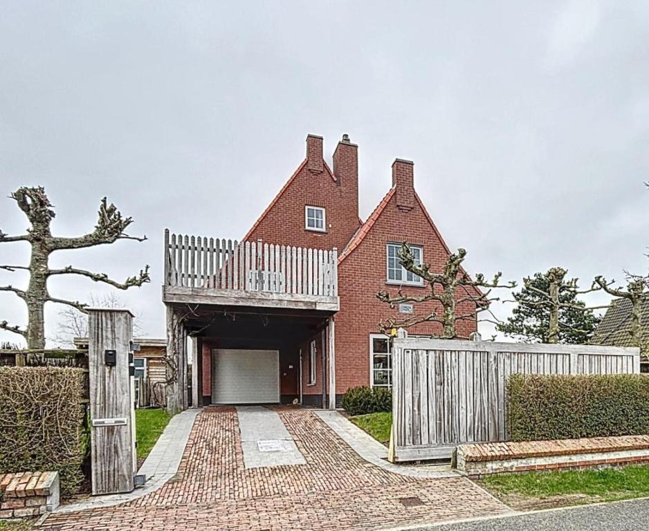 a red brick house with a white fence at Villa Charme - Koksijde in Koksijde